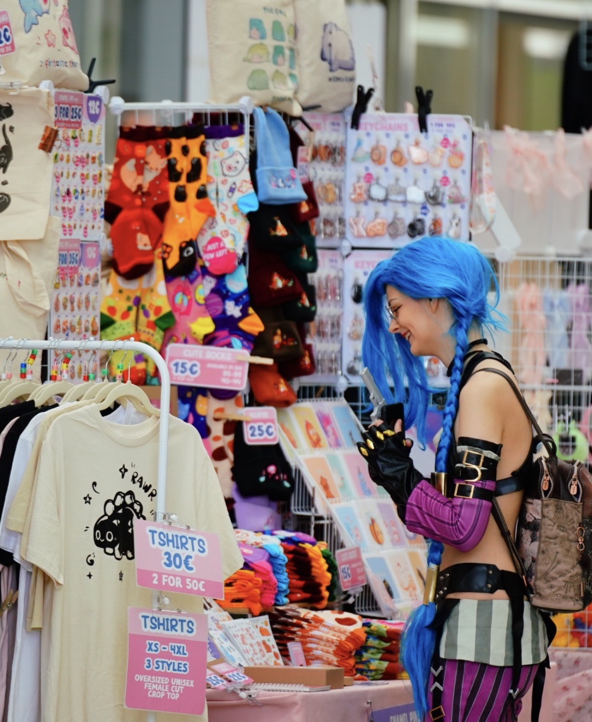Anime-Merch-Stand mit Stickern, Socken, Keychains und Cosplayerin